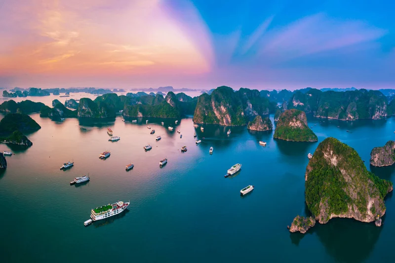 Toàn cảnh Vịnh Hạ Long với những đảo đá vôi và du thuyền vào lúc hoàng hôn