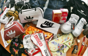Hàng giả Trung Quốc nhái các thương hiệu nổi tiếng như Adidas, Nike, Dior, Dolce & Gabbana, Giorgio Armani và Escada, bao gồm túi xách, giày, nước hoa, đồng hồ và quần áo, với biển hiệu "FAKE" đặt ở giữa.