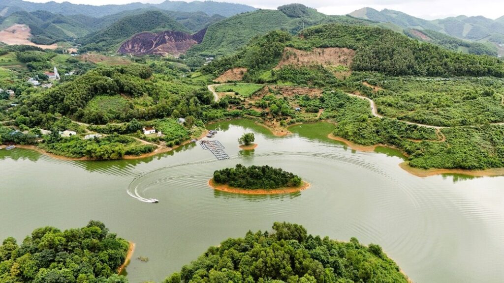 Hình ảnh hồ nước ở Thái nguyên, có đảo nổi, cây xanh bao quanh và thuyền đang chạy trên hồ